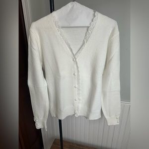 White cardigan with pearl and lace accents on buttons and sleeves.